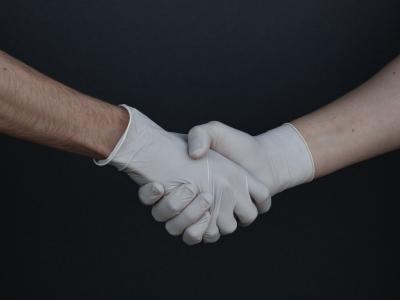 People Shaking Hands in Latex Gloves by Branimir Balogovic